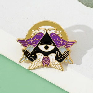 Detail of Cthulhu Angel enamel pin featuring a black Eye of Providence with purple wings