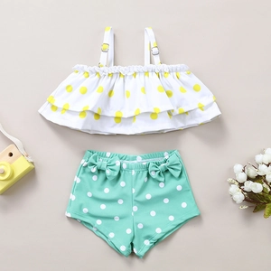 Detail of kids two-piece swimsuit with ruffle polka dot top and mint green bow trunks