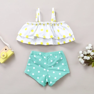 Flat lay of two-piece toddler swimsuit with ruffle straps, polka dots and mint green bottoms