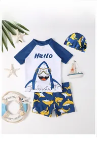 Detailed flat lay of three-piece boys shark swimsuit with top shorts and swim cap