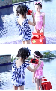 Detail of girls' navy striped swimwear with ruffle sleeves and bow headbands by a pool