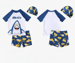 Three-piece boys' swimwear set with blue shark print top, matching trunks, and swim cap