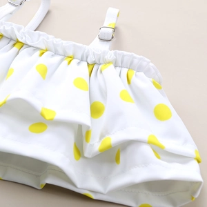 Detailed view of yellow polka dot ruffles and adjustable straps on children's swimwear