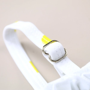 Detail of swimsuit shoulder strap with yellow polka dots and adjustable metal buckle