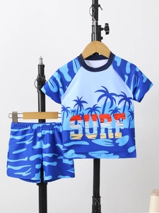 Detail of boys' quick-dry swimwear featuring blue coconut tree print and SURF lettering