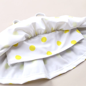Close-up of yellow polka dot ruffle detail on toddler girl's swimwear fabric