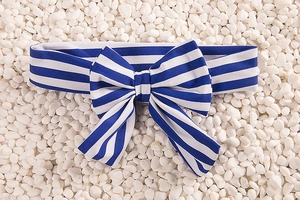 Detail of blue and white nautical striped bow headband on white pebble background