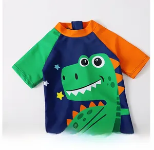 Detail of round neckline and green cartoon dinosaur print on blue toddler swimwear