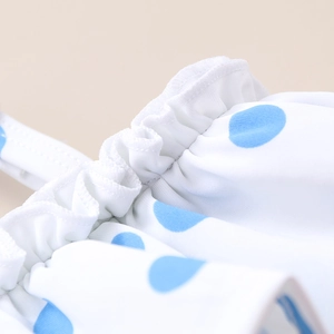 Detail of blue polka dot pattern and ruffled edge on kids swimwear fabric