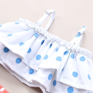 Close-up of blue polka dots on white ruffled kids swimwear with adjustable strap