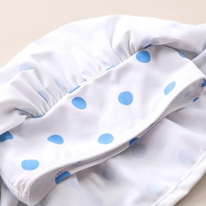 Detailed view of blue polka dot swimsuit fabric with ruffle edge and fine stitching