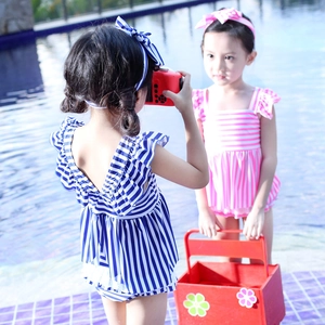 Striped toddler girls swimwear set with ruffles and matching bow headband outdoors