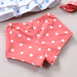 Detail of coral pink polka dot swim shorts and ruffled top for toddler girls