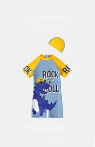 Detail of blue cartoon dinosaur kids swimsuit with short sleeves and matching swim cap