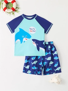 Flat lay of boys' blue sun protection swimwear with shark prints and vacation props