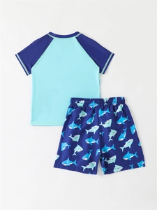 Detail of boys' two-piece swimsuit featuring blue shark print shorts and sun protection top