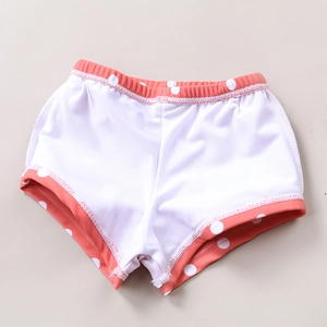 Close-up of coral pink polka dot swim shorts with soft white inner lining for kids