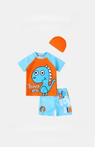 Detailed flat lay of boys three-piece dinosaur swimsuit with top, shorts, and swim cap