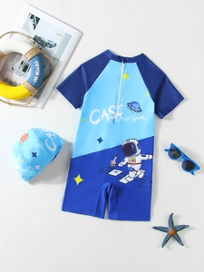 Flat lay of boys' astronaut one-piece swimsuit and matching swim cap with summer props