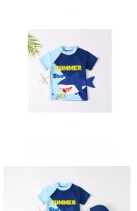 Short sleeve kids shark swimsuit and hat set laid flat with beach decor