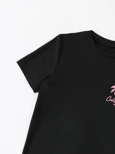 Close-up of black kids' swim shirt featuring pink Cali logo and palm tree detail