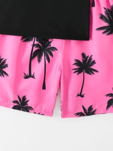 Detail of kids two-piece swimsuit with black top and pink coconut tree print shorts