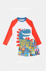 Detail of boys' long sleeve rash guard with cool dinosaur print and colorful swim trunks
