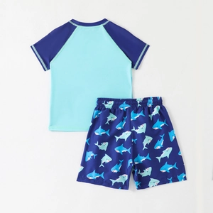 Two-piece boys short sleeve swimsuit set with blue shark print trunks and rash guard