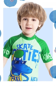 Detail view of cartoon crocodile print on kids short sleeve green swimsuit with graffiti text
