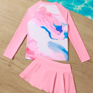 Pink tie-dye long sleeve two-piece girls' swimwear with pleated skirt on wood background
