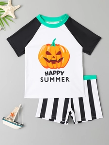 Flat lay of boys' swimwear with pumpkin print raglan top and striped swim shorts