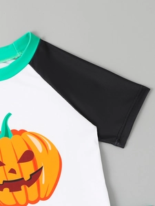Close-up of boys Halloween swimwear featuring a pumpkin print and raglan sleeve detail