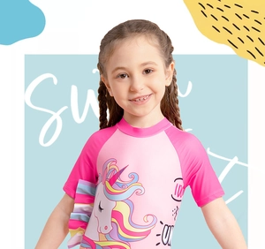 Detail of pink girls' one-piece swimsuit featuring a colorful unicorn and rainbow ruffles