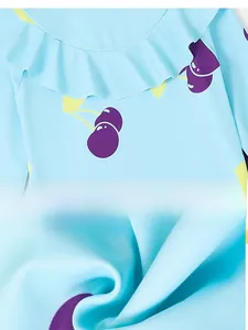 Close-up of girls' swimwear featuring ruffle collar with cherry print and elastic fabric