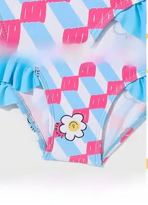 Detail of blue striped girls swimsuit featuring pink ruffles and summer sun graphic