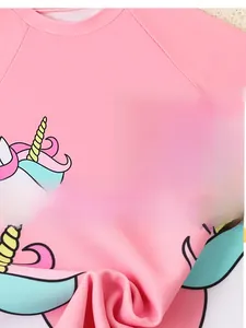 Detail of pink girls' swimwear fabric showing a colorful unicorn print and soft texture