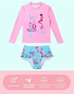 Detail of girls two-piece swimsuit with long-sleeve flamingo top and ruffled blue bottoms