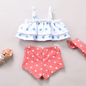 Detailed flat lay of a girls three-piece polka dot swimsuit with headband and ruffle top