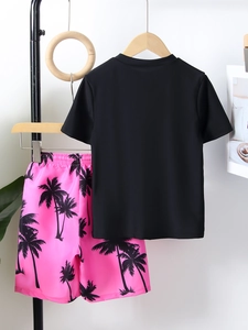 Detail of boy's black T-shirt and pink tropical palm tree print beach shorts set