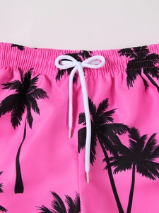 Close-up of pink swim shorts with black palm tree prints and white drawstring waist
