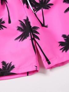 Detail of pink boys beach shorts with black coconut tree print and white drawstring