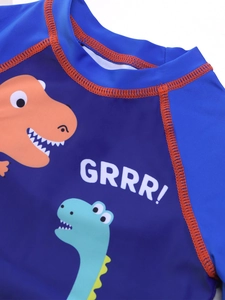 Detail of blue boys swimwear showing orange dinosaur print and decorative stitching