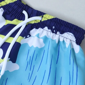 Close-up of quick-dry swim shorts with elastic waistband, white drawstring and wave print
