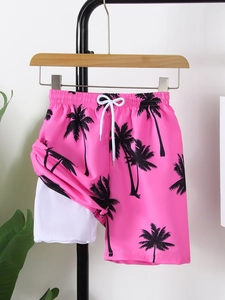 Detail view of pink boy's swim trunks featuring black palm prints and white drawstring