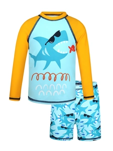Detailed flat lay of blue cartoon shark print long sleeve top and matching boys swim shorts