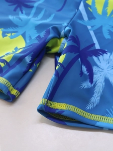 Detail of boys' swim shorts featuring tropical coconut tree print and durable double stitching