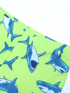 Detail van neon groene jongens zwembroek met blauwe en witte cartoon haaienprints