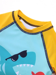 Detail of blue collar with flatlock stitching and cartoon shark print on kids' swimwear