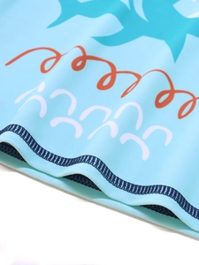 Detailed close-up of blue shark print and double-stitched hem on kids swimwear
