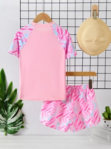 Detail of girls two-piece pink swimsuit set with floral short sleeves and printed shorts